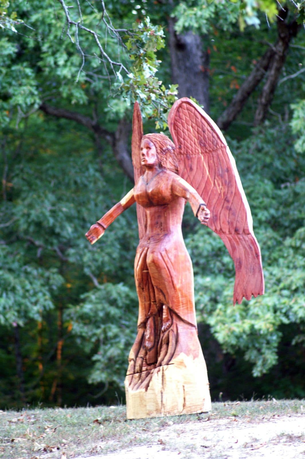 Tall red cedar angel carving with arms outstretched and full feathered wings