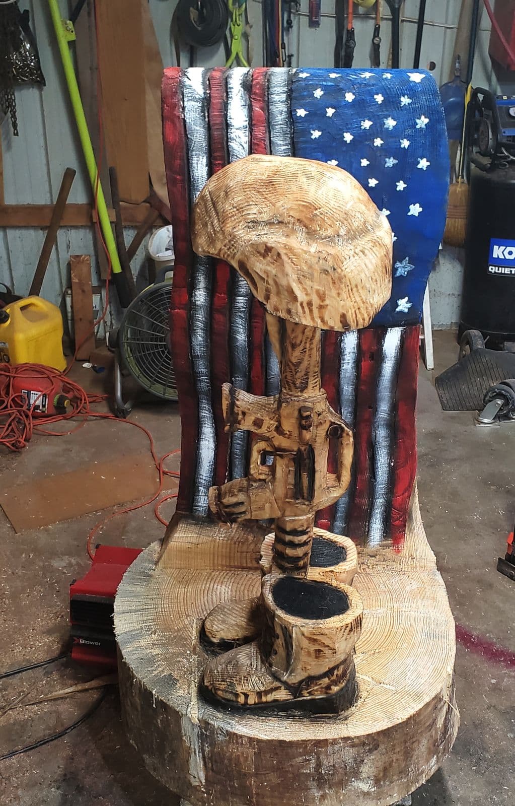 Carved helmet, rifle and boots in front of a painted American flag