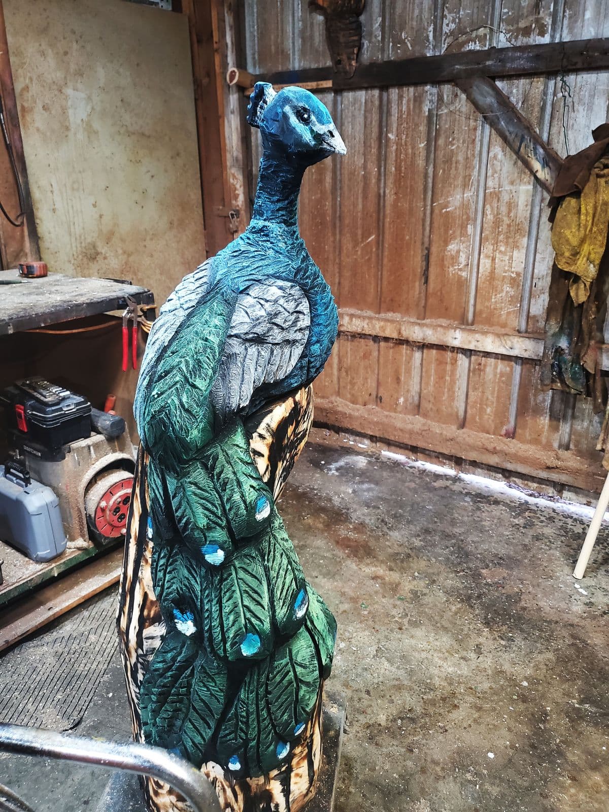 Peacock carving painted in blues and greens with a long tail